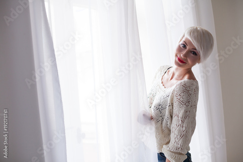 blonde with short hair stands at the window photo