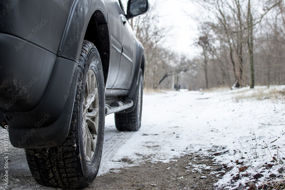 foreground wheel of an SUV, on a background of a snowy landscape