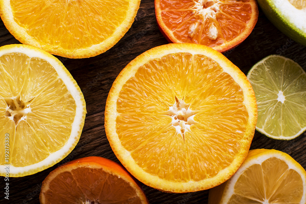 Fototapeta premium colorful citrus fruits, cut in half, on a dark old board