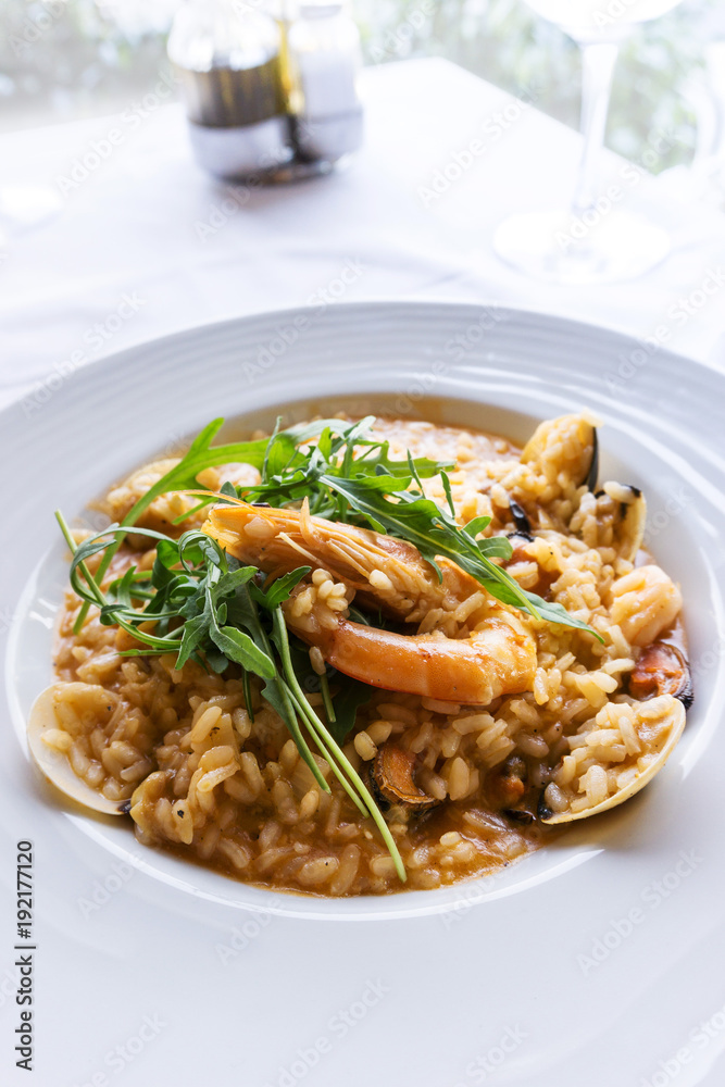 Tasty risotto with Shrimp, fresh herbs vegetables on a white plate Tasty risotto with Shrimp, fresh herbs vegetables on a white plate