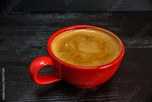 fresh aromatic coffee in a red mug on a black wooden background
