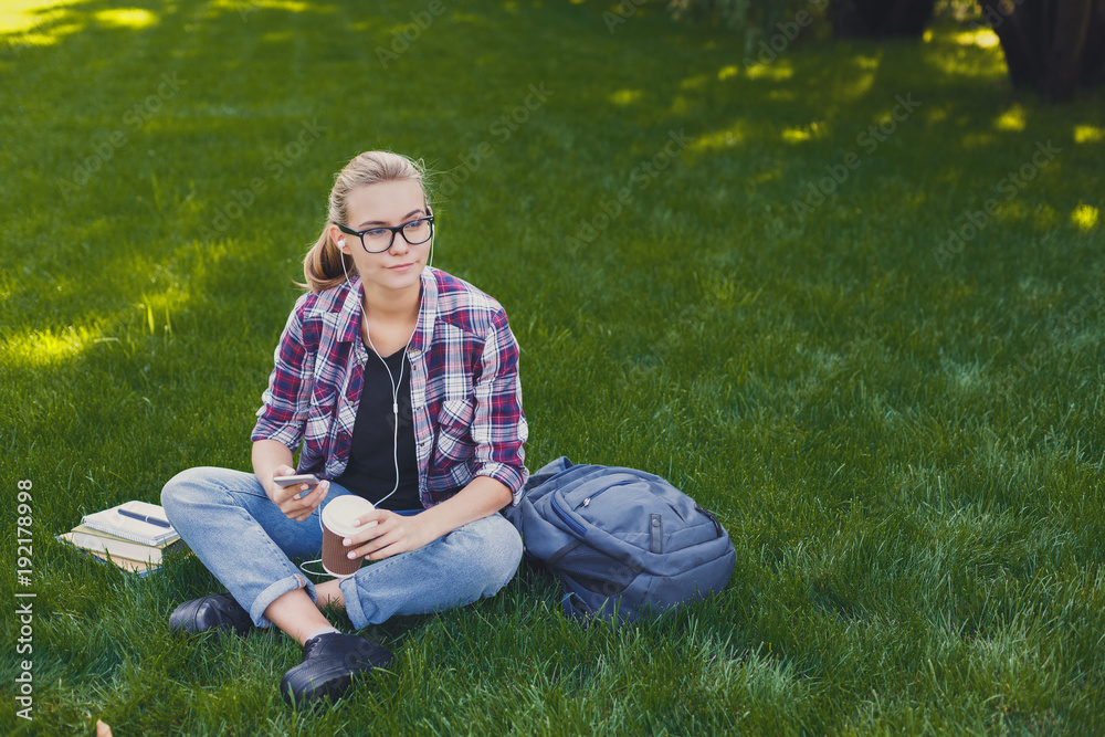 Young woman listening to music on grass outdoors