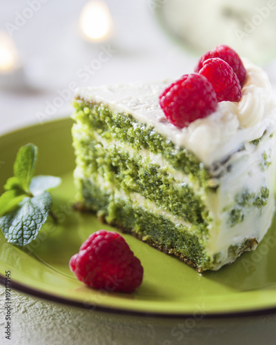 Homemade spinach crepe cake with cheese cream close-up on a plate on a table.