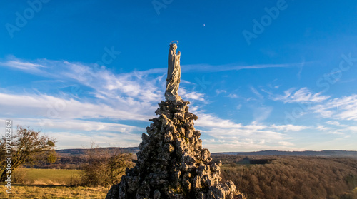 Quadro em tela Wide angle shot from low angle of view of a Virgin Mary statue with moon and clouds on background