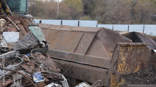 Sorting and loading of scrap metal/Excavator is loading scrap metal junk into a bin at a garbage dump or recycling center.