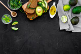 Breakfast for safety weight loss. Avocado toast with rye bread, lime, olive oil and greens on black background top view space for text