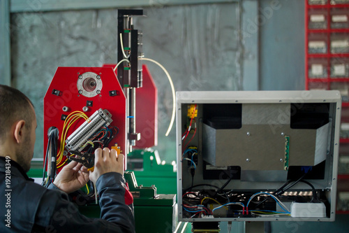 Electrician works with energy panel and machinery equipment on plant photo