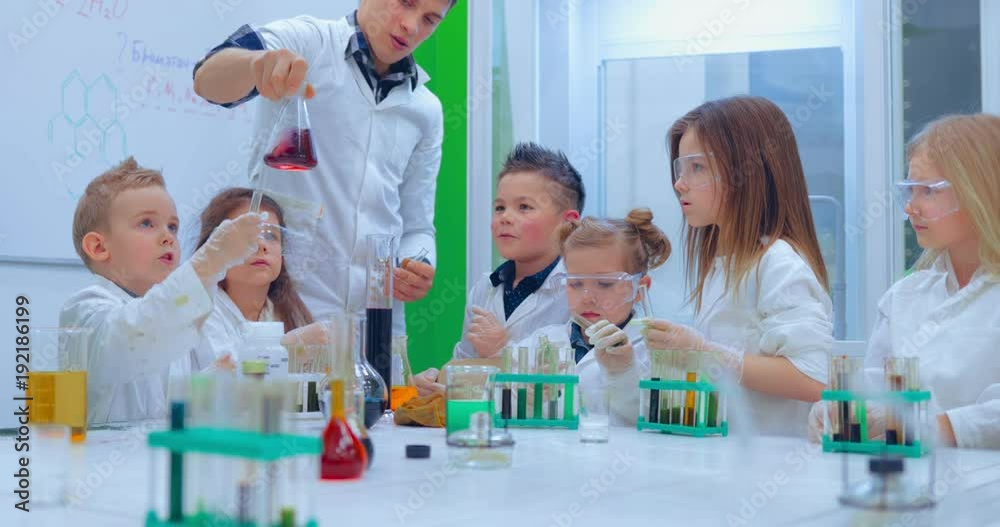 Young boys and girls is making chemistry experiments. Teacher and children in chemistry class Young boys and girls is making chemistry experiments. Teacher and children in chemistry class