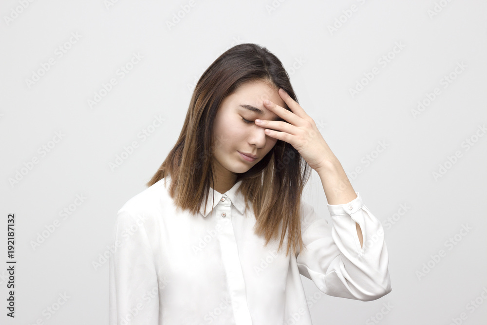 Indoor portrait of sad and disappointed young asian woman covering her face with hands in white formal shirt. Emotions, feelings, lifestyle concept. Indoor portrait of sad and disappointed young asian woman covering her face with hands in white formal shirt. Emotions, feelings, lifestyle concept.