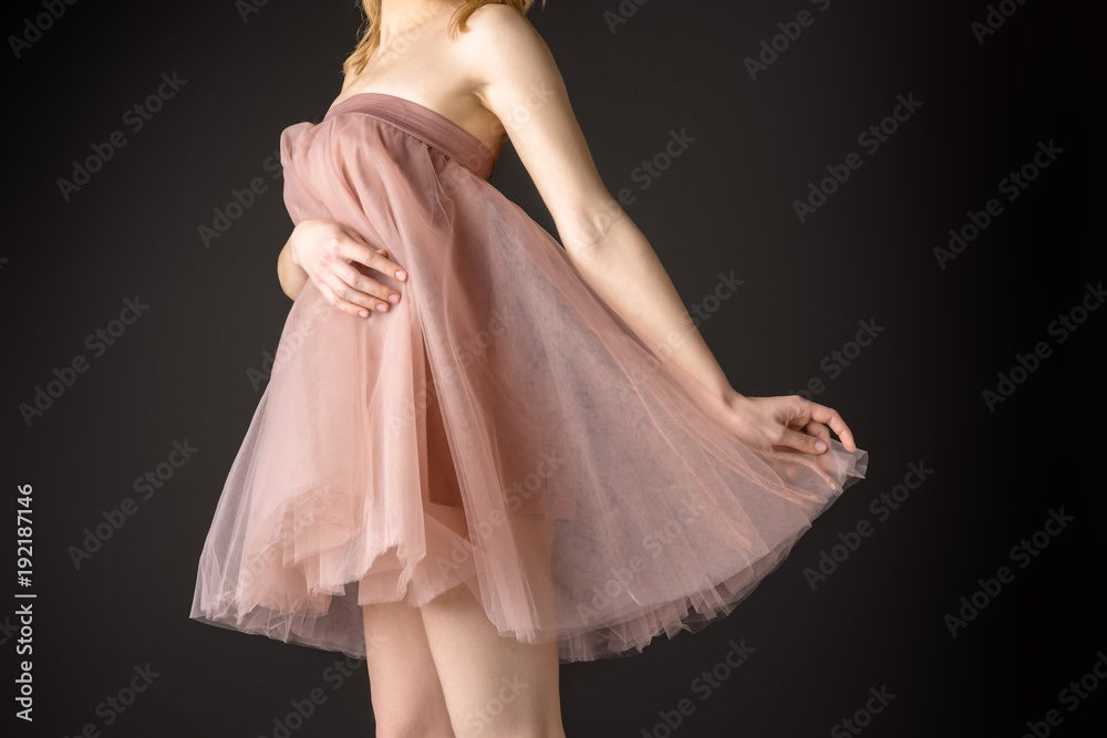 midsection view of tender girl posing in pink chiffon dress, isolated on grey