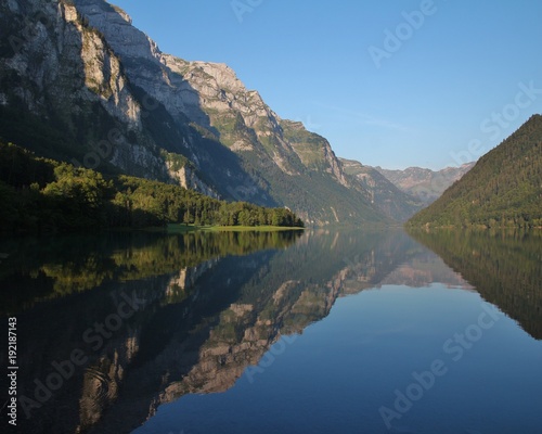 Summer morning at lake Klontalersee  Switzerland. Mountain range mirroring on the surface.