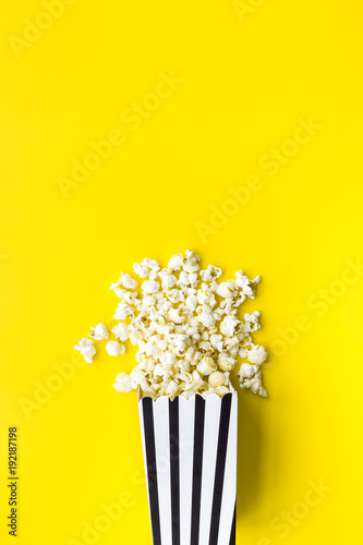 Fototapeta Naklejka Na Ścianę i Meble -  Popcorn in paper bag scattered on yellow background top view copy space
