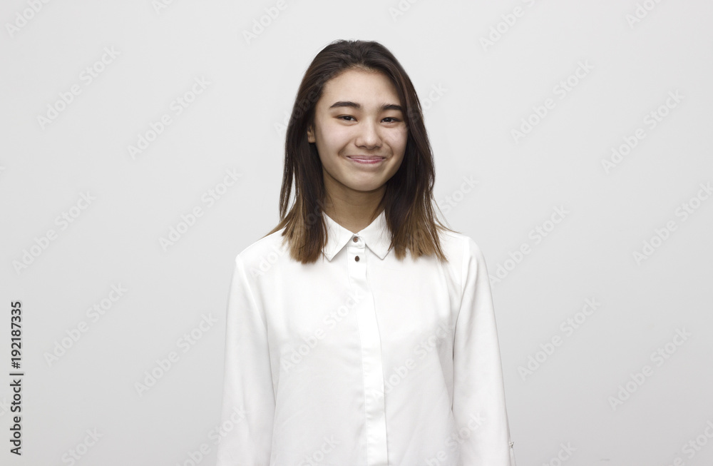 Indoor portrait of young attractive and happy woman smiling in white formal shirt on the white background. Emotions, feelings, lifestyle concept Indoor portrait of young attractive and happy woman smiling in white formal shirt on the white background. Emotions, feelings, lifestyle concept