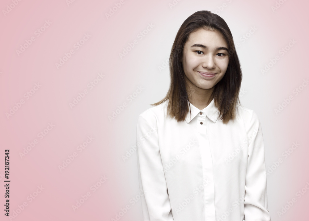 Indoor portrait of young attractive shy woman smiling in white formal shirt on the rose background. Emotions, feelings, lifestyle concept Indoor portrait of young attractive shy woman smiling in white formal shirt on the rose background. Emotions, feelings, lifestyle concept