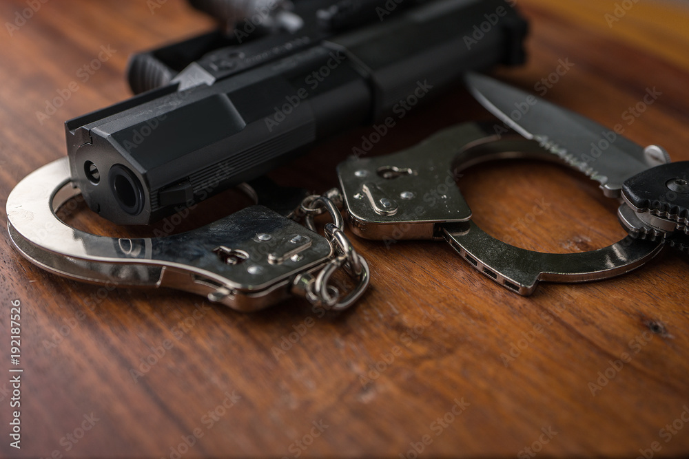 Obraz premium Tactical gear set of Pistol gun knift handcuff and clock on wooden background. Police or military equipment concept.