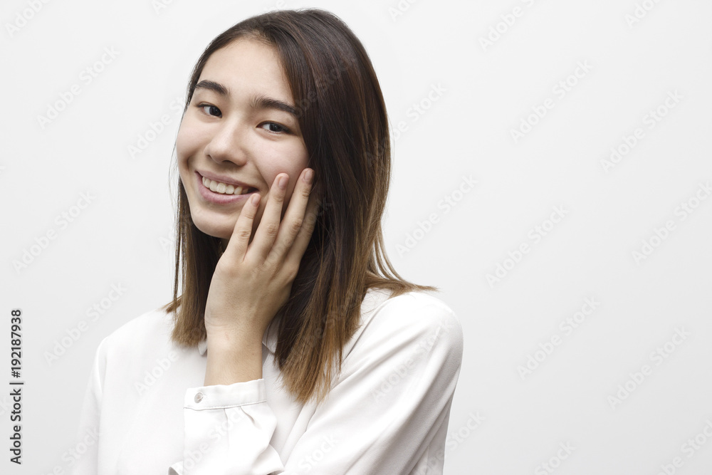 Portrait of beautiful young brunette woman touching her cheek, looking at camera and smiling. Beauty healthcare and skin care concept Portrait of beautiful young brunette woman touching her cheek, looking at camera and smiling. Beauty healthcare and skin care concept