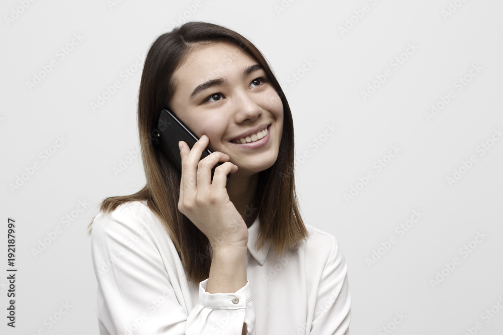 Attractive young woman in white shirt talking on mobile phone and smiling wide. Technology and joy concept Attractive young woman in white shirt talking on mobile phone and smiling wide. Technology and joy concept
