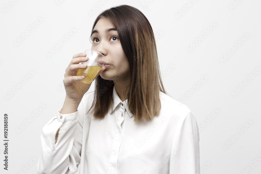 Indoor portrait of young beautiful woman drinking apple juice from plastic vase. Food and beverages concept
