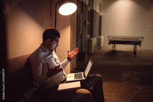 Portrait of surprised young european guy at modern office workplace. Bad news, problem, trouble, failure concept