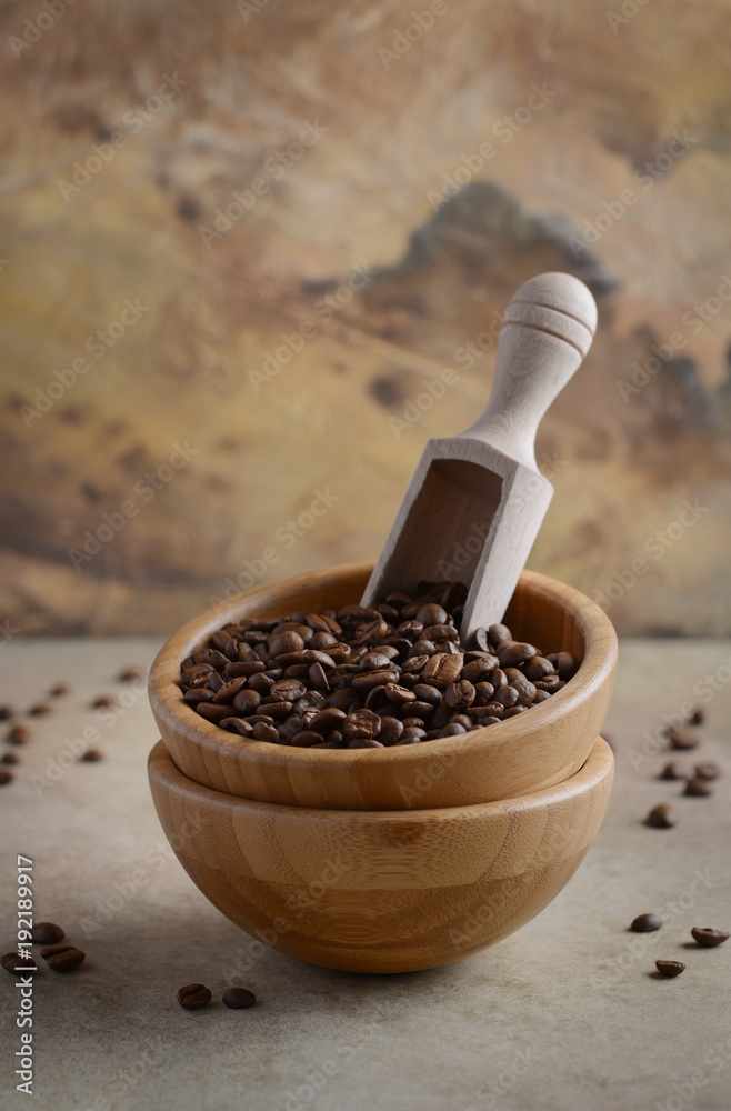 Roasted coffee beans in a wooden bowl on concrete background, selective focus, copy space.