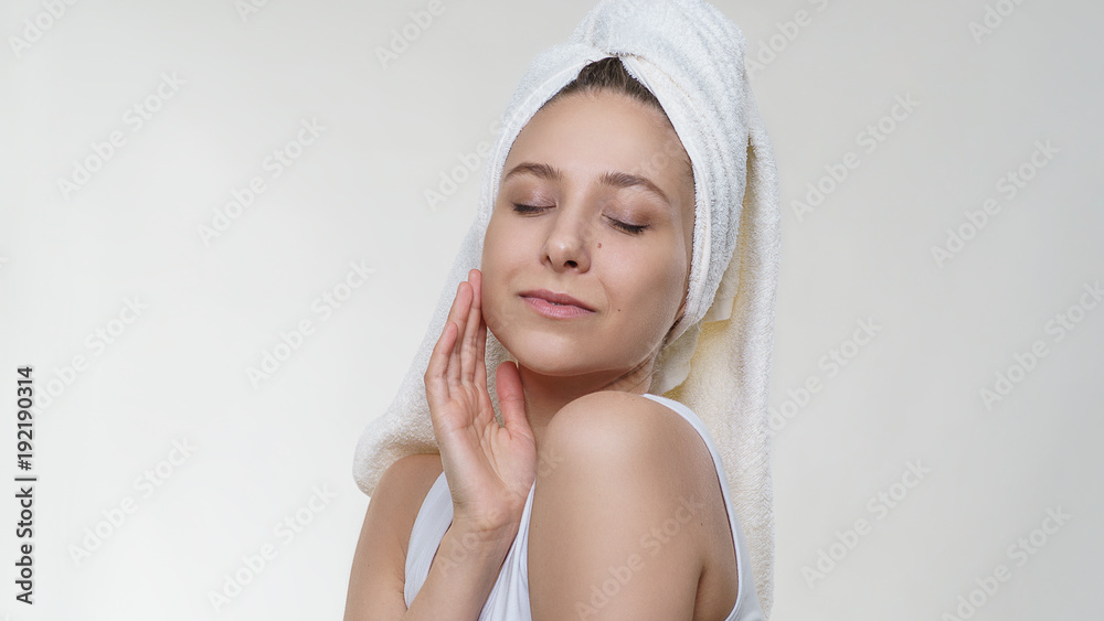 Pretty amazing woman with perfect clean skin in a towel tenderness posing with happy smile on white background. Spa healthcare portrait photography