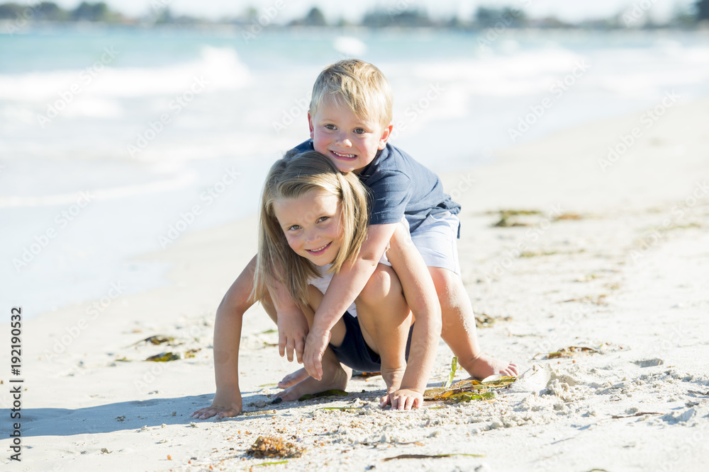 little adorable and sweet siblings playing together in sand beach with small brother hugging his beautiful blond young sister enjoying holidays little adorable and sweet siblings playing together in sand beach with small brother hugging his beautiful blond young sister enjoying holidays