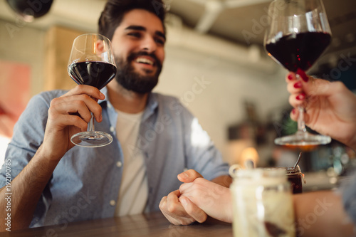 Couple drinking red wine in cafe and celebrating anniversary or Valentine's day. Couple holding each other for hand.