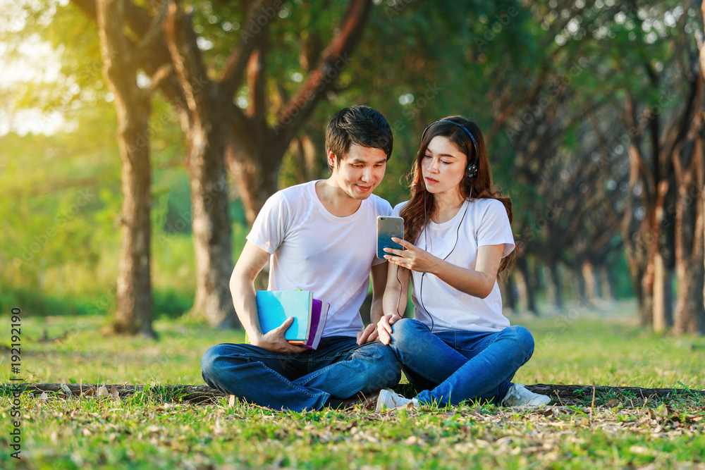 couple listening music from mobile with headphone in the park