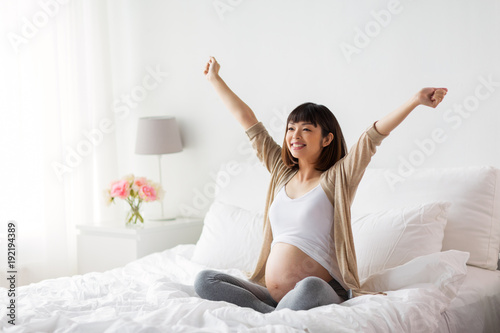 Wallpaper Mural happy pregnant asian woman sitting in bed at home Torontodigital.ca