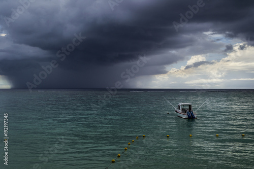 sea with anchoring boat and dark storm clouds on the horizon