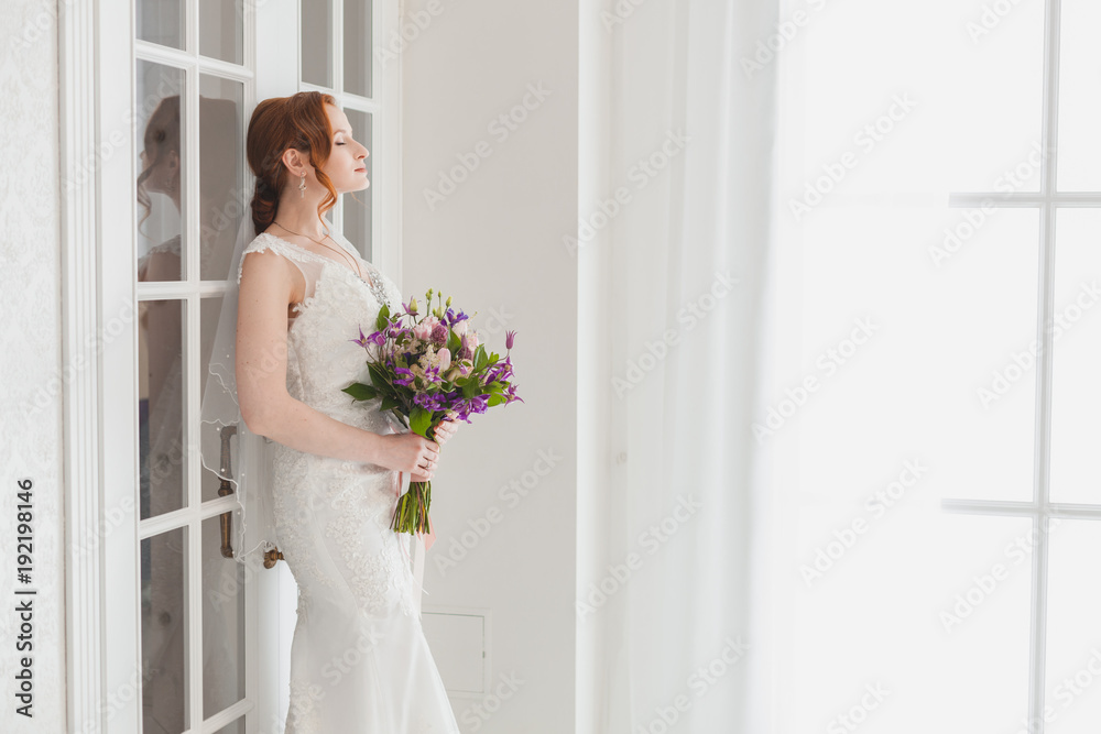 Gentle bride waiting for the groom standing near the door.