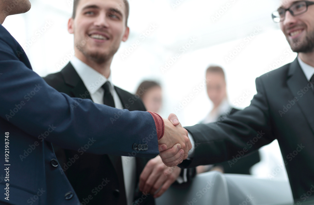 Partners concluding deal and shaking hands in the presence of team members Partners concluding deal and shaking hands in the presence of team members