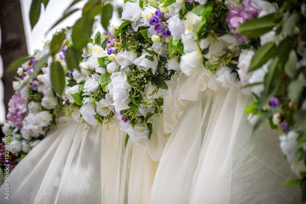 Wedding arch decorated with flowers, white chairs and flowers bouquet