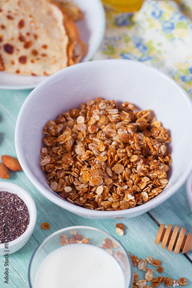 breakfast with home made granola and pancakes on turquoise surface breakfast with home made granola and pancakes on turquoise surface