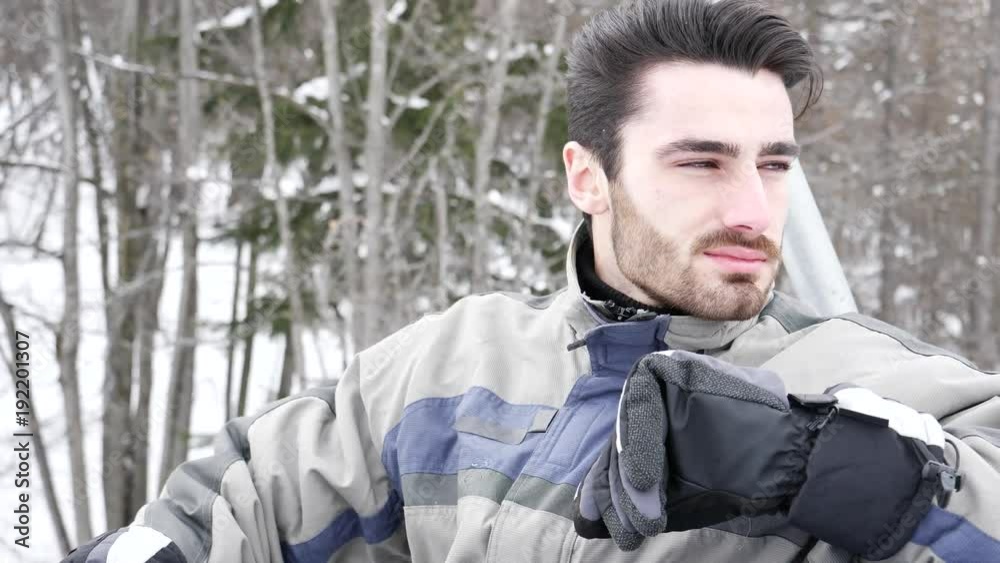 Portrait of handsome man in skiing suit sitting on chairlift rising up and looking at camera. Portrait of handsome man in skiing suit sitting on chairlift rising up and looking at camera.