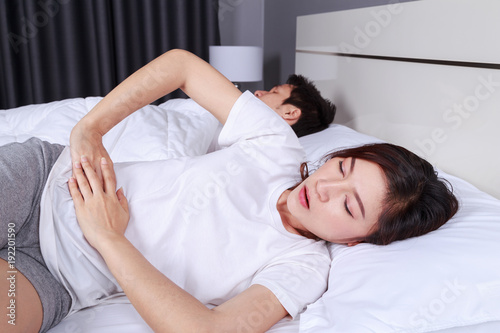 woman stomach pain on bed with her hunsband