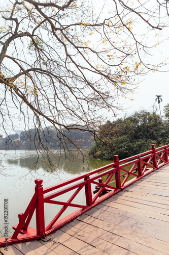 Red Bridge at Hoan Kiem Lake with tress and reflected shadow and branches in foreground in Hanoi, Vietnam.