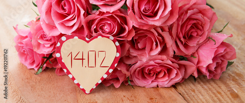 Valentine's Day background with pink roses over wooden table.