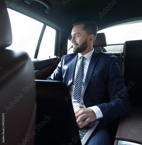 Smiling businessman with laptop sitting in car © ASDF