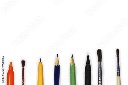 Stationery. Pencils, pen, brushes, felt-tip pen. From above. On a white background.