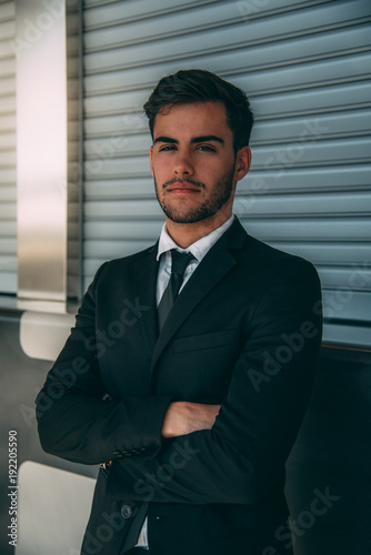 Young business man standing with the suitcase at the airport waiting for the flight .