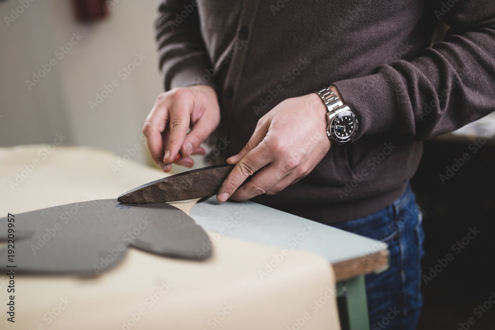 Close up of a male shoemaker working with leather textile at his workshop. Close up of a male shoemaker working with leather textile at his workshop.