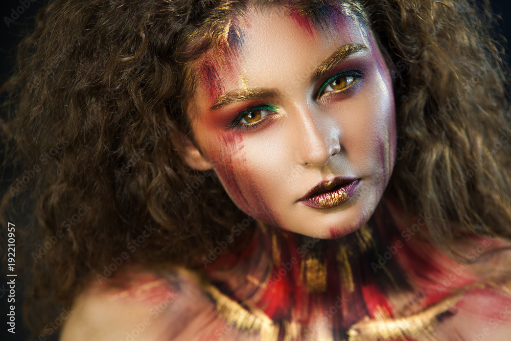 Fototapeta premium beautiful curly girl in a fire makeup and green shadows under the cloak image created by a make-up artist
