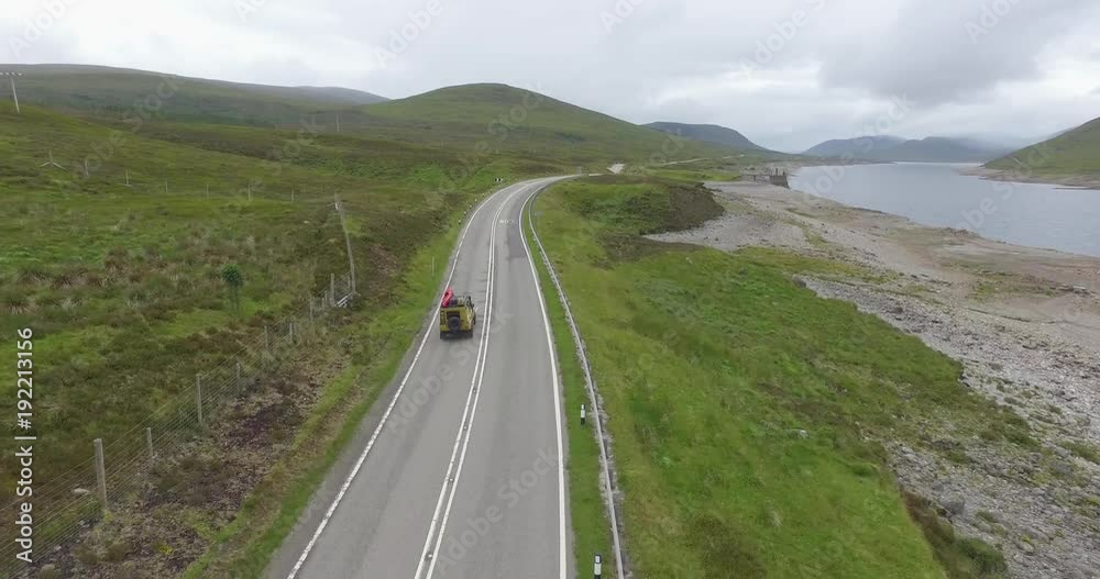 Drone shot of 4X4 cruising along country highway over beautiful landscape Drone shot of 4X4 cruising along country highway over beautiful landscape