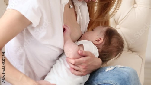 Mother breast feeding and hugging her baby.Young mother feeding breast her babyboy at home in white room. Mom breastfeeding her child whith breast milk photo