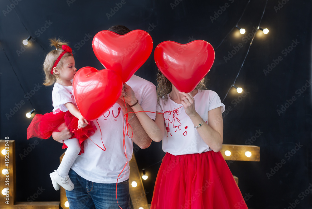 Young beautiful parents with baby girl playing, holiday balloons. St. Valentine's Day