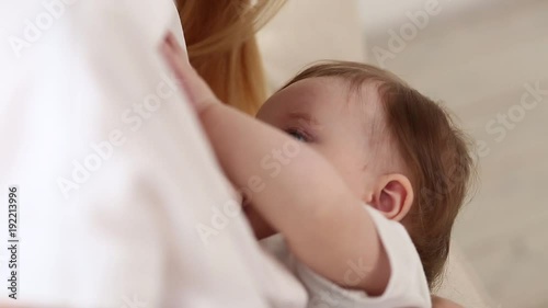 Mother breast feeding and hugging her baby.Young mother feeding breast her babyboy at home in white room. Mom breastfeeding her child whith breast milk photo