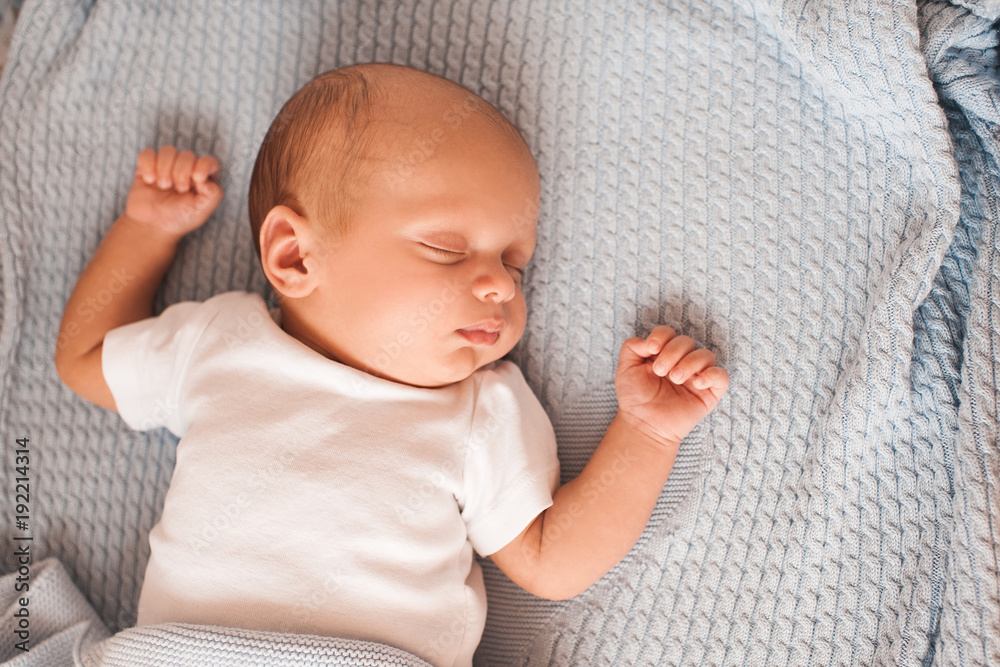 Sleeping baby lying in bed on knitted blanket closeup. Top view. Sleeping baby lying in bed on knitted blanket closeup. Top view.