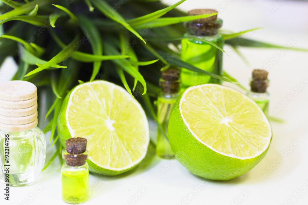 Lime oil skin and hair care home spa. Bottle of oil, green leaf. White board background Lime oil skin and hair care home spa. Bottle of oil, green leaf. White board background