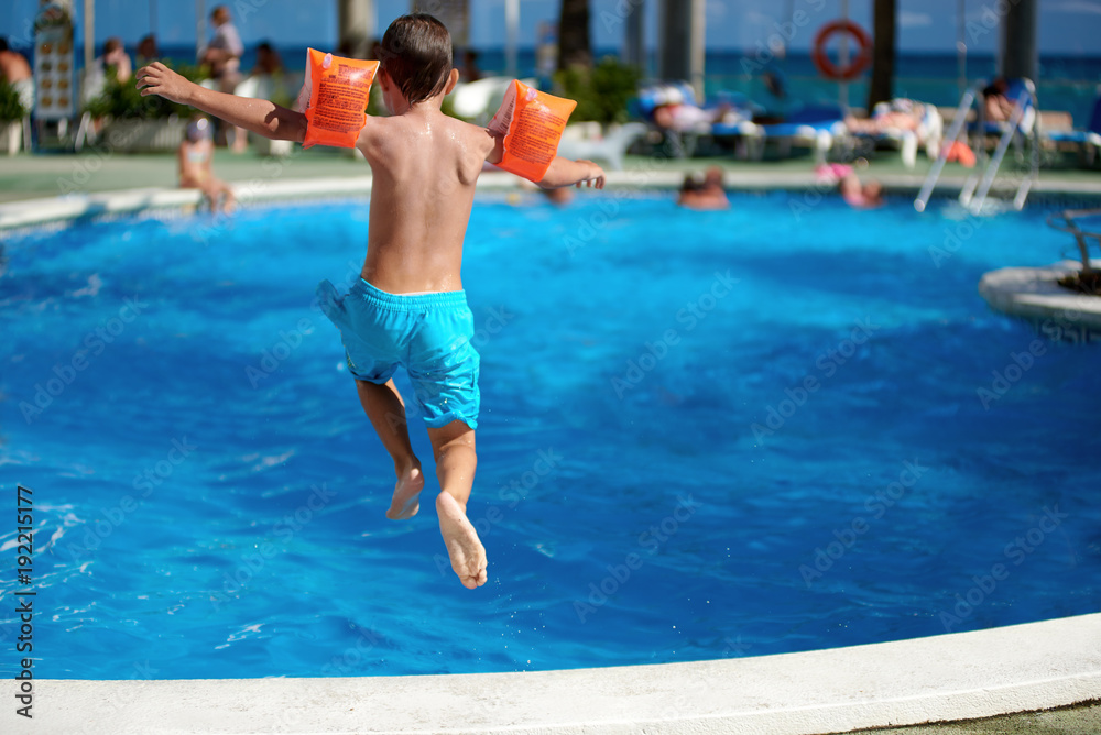 Caucasian boy having fun jumping into the pool.